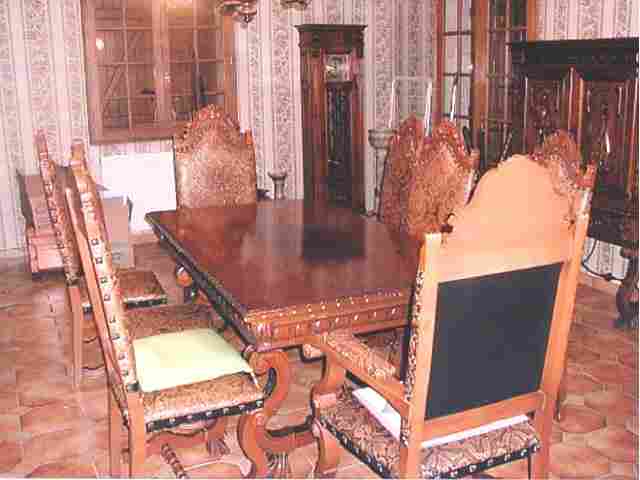 Salle à manger complète, style Renaissance Espagnole en merisier comprenant : six chaises, deux fauteuils cuir, une grande table, un bahut bas quatre portes, un vaisselier, une pendule et un lustre.